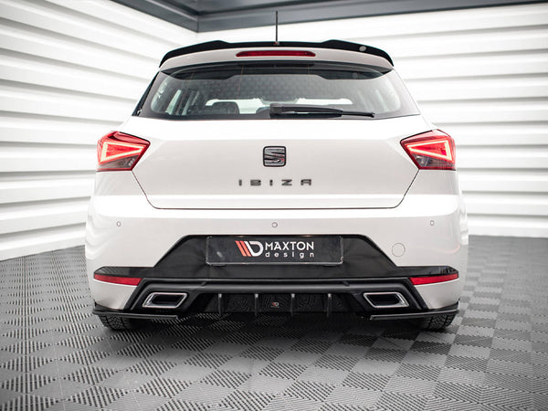 A white car is parked in a showroom. The rear features the text "IBIZA" and "MAXTON design," with distinct taillights and a sleek bumper. The room has checkered flooring.