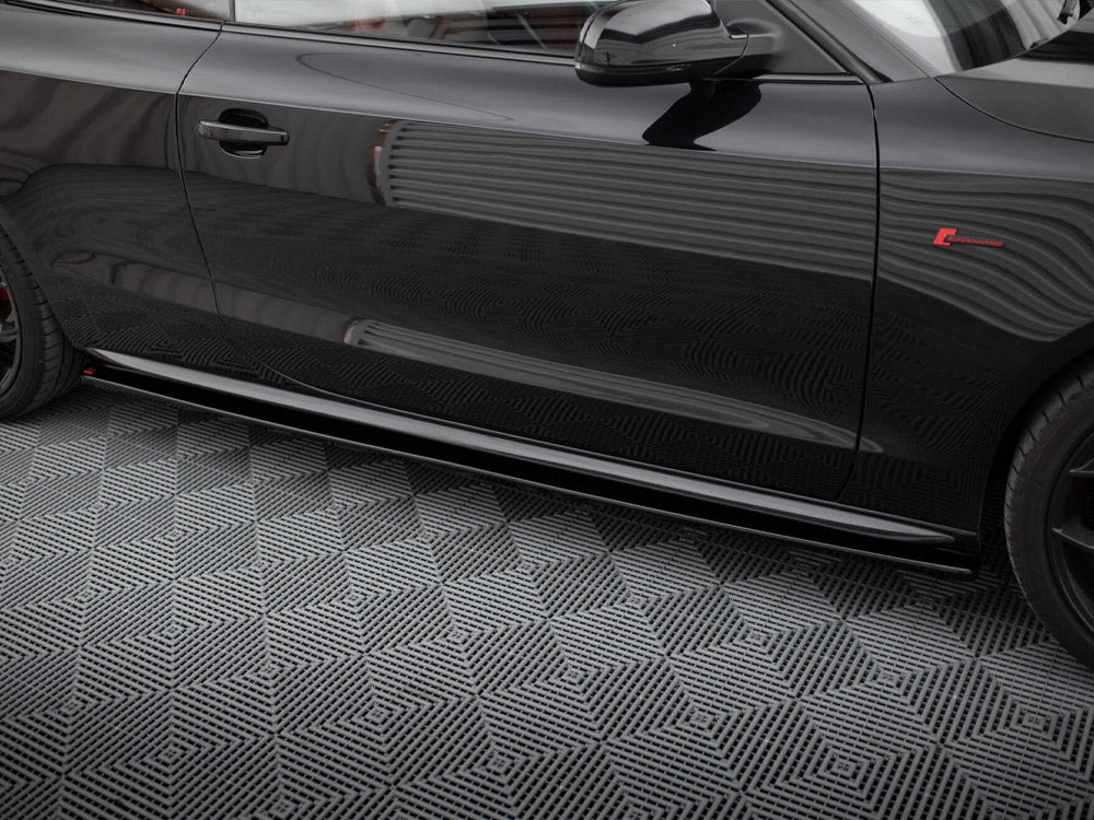 A shiny black car door with reflections parked on a patterned grey floor. The car features a red emblem and sleek design lines.