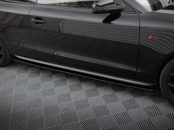 A shiny black car door with reflections parked on a patterned grey floor. The car features a red emblem and sleek design lines.