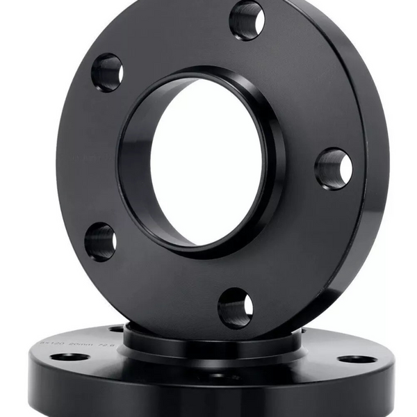 Two black metal flanges with central circular openings and bolt holes are stacked, with one slightly tilted. The surface reflects light, set against a plain white background.