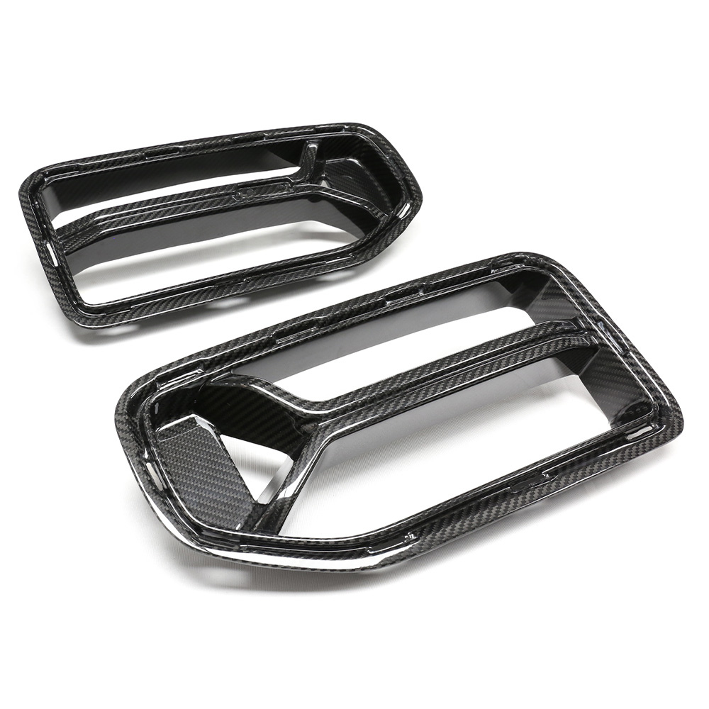 Two carbon fiber air intake covers with rectangular openings lie on a flat, white surface. The glossy finish highlights their texture, designed for automotive use, suggesting a performance-focused application.