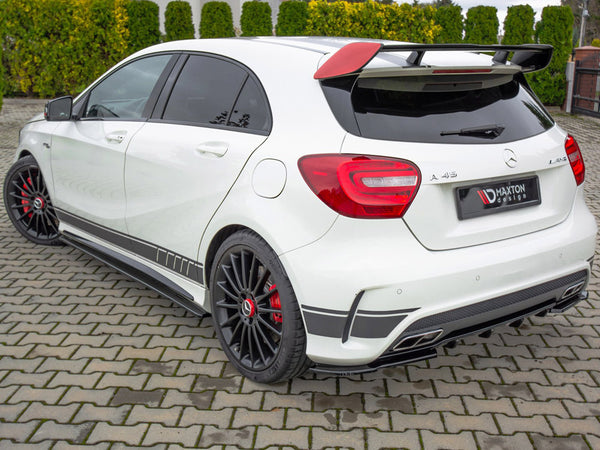 White Mercedes-Benz A45 AMG with a rear spoiler and black alloy wheels parked on a paved driveway. Background features neatly trimmed green hedges. License plate reads "MAXTON design."
