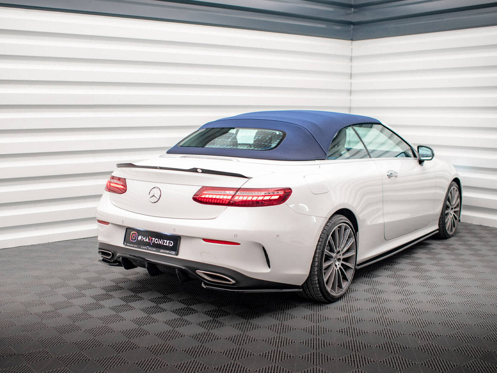 A white convertible car with a blue soft top is parked in a modern showroom with patterned flooring and white paneled walls. Visible text: "MATIONIZED" on the license plate.