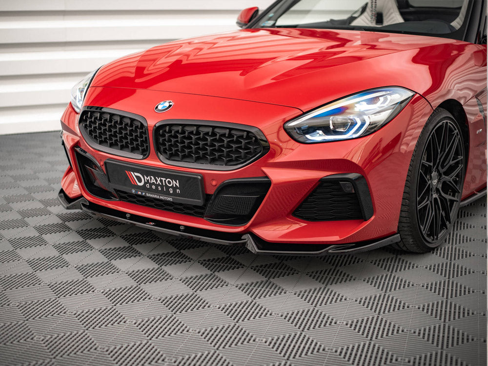 A red sports car with sleek design and illuminated headlights is stationary on a textured gray floor. The front grille displays a badge, and "MAXTON design" is visible on the license plate area.