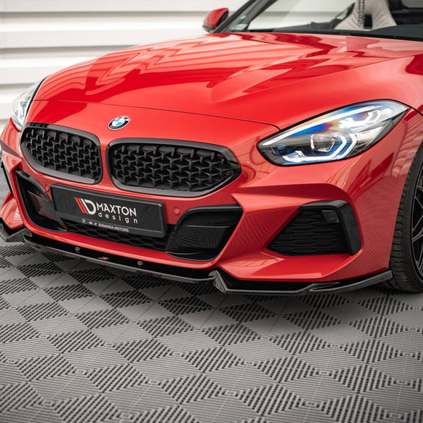 A red sports car with sleek design and illuminated headlights is stationary on a textured gray floor. The front grille displays a badge, and "MAXTON design" is visible on the license plate area.