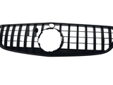 A black car grille features vertical and horizontal slats forming a rectangular pattern, with a circular opening in the center, set against a plain white background.