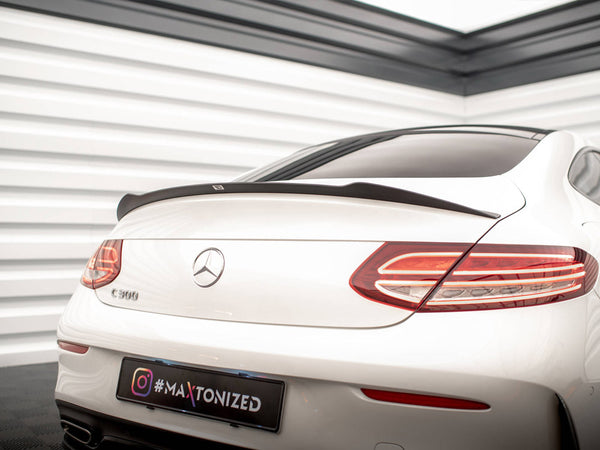 A white Mercedes-Benz C 300 is parked indoors, showcasing its rear with sleek taillights and a spoiler. The environment includes white paneled walls. The license plate reads "#MAXTONIZED".