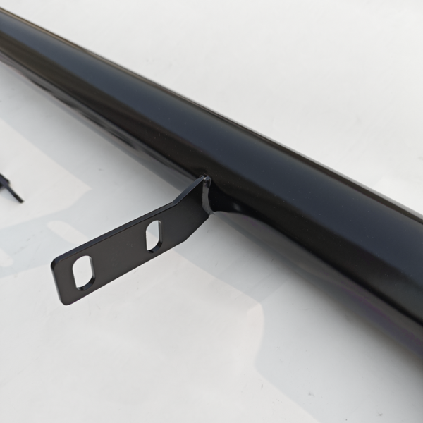 A black metal rod with two bracket holes protrudes from its side, resting on a white surface with shadowy reflections.