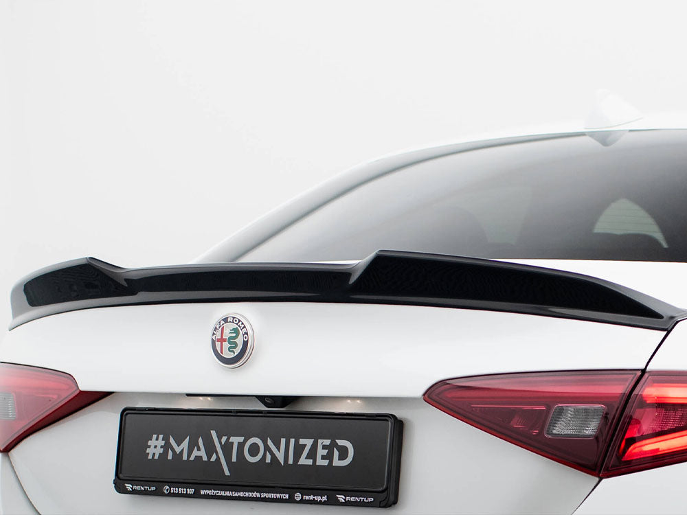 A white car has a black spoiler attached to its trunk. The logo "ALFA ROMEO" is visible, along with "#MAXTONIZED" text on the license plate. The background is plain white.