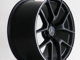 A black alloy wheel features a multi-spoke design with a Mercedes emblem at the center, placed against a simple white background.