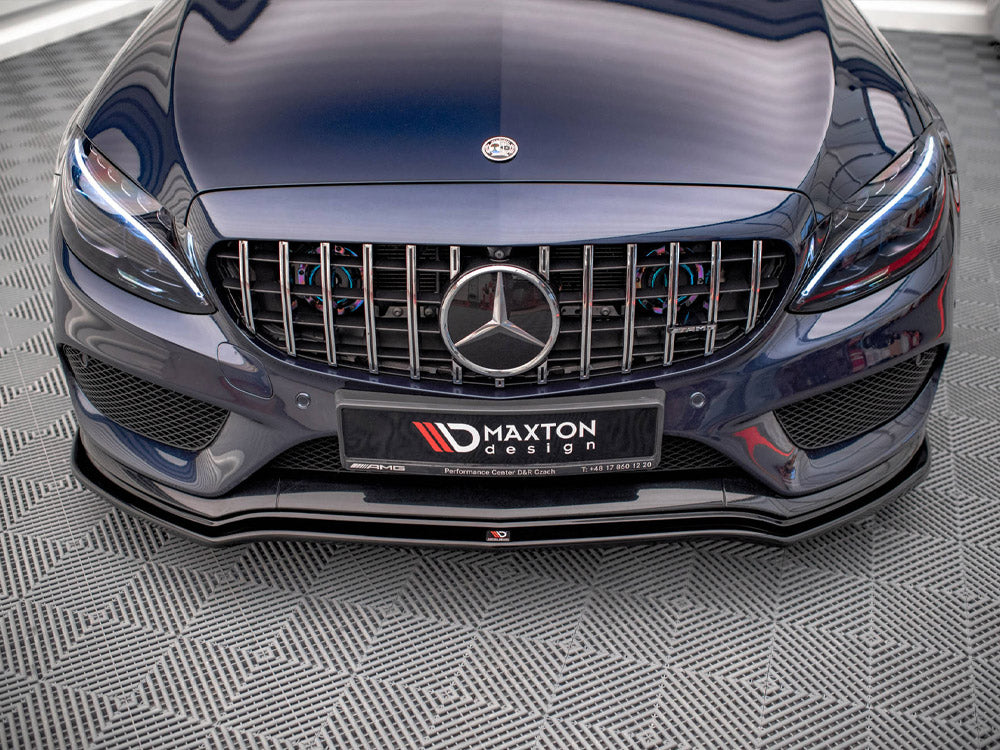 A dark blue car with a prominent front grille displaying a circular emblem sits on a textured floor. The license plate reads "MAXTON design" with contact information and AMG branding.