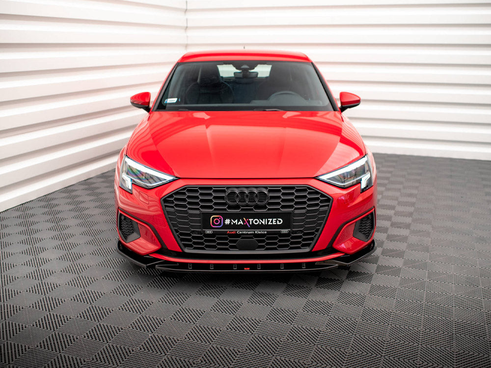 Red car displayed stationary in a white-paneled showroom with a textured grey floor. The license plate reads "#MAXTONIZED Audi Centrum Kielce."