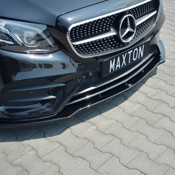 Car front with grille and headlights, parked on a paved surface. The license plate displays the text “MAXTON.”