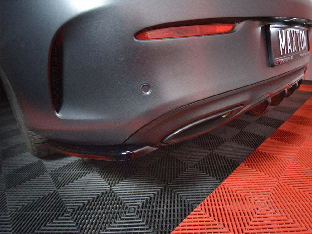 Car's rear bumper with a "MAXTON" license plate, resting on a checkered black-and-red floor.