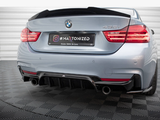 The rear of a silver BMW 435i with dual exhausts and illuminated taillights. It is parked on a patterned floor. The license plate reads: 