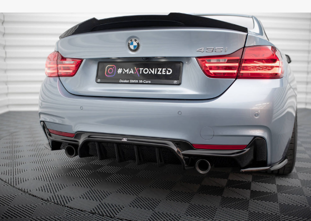 The rear of a silver BMW 435i with dual exhausts and illuminated taillights. It is parked on a patterned floor. The license plate reads: "#MAXTONIZED Dealer BMW M Cars."