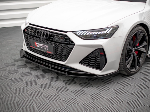 A white car with sleek headlights and a black grille, featuring the text "Maxton Design." It is parked indoors on a patterned floor, showcasing modern design and detailing.