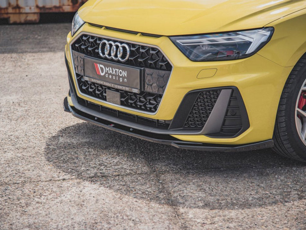A yellow car's front view, featuring an Audi logo, sporty grille, and headlight on a textured pavement. The license plate reads "MAXTON design AUTO SPECIAL KRZYSZ 72 859 20 50."