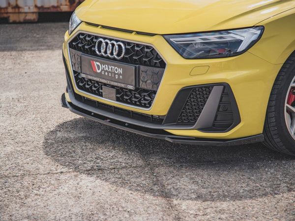 A yellow car's front view, featuring an Audi logo, sporty grille, and headlight on a textured pavement. The license plate reads "MAXTON design AUTO SPECIAL KRZYSZ 72 859 20 50."