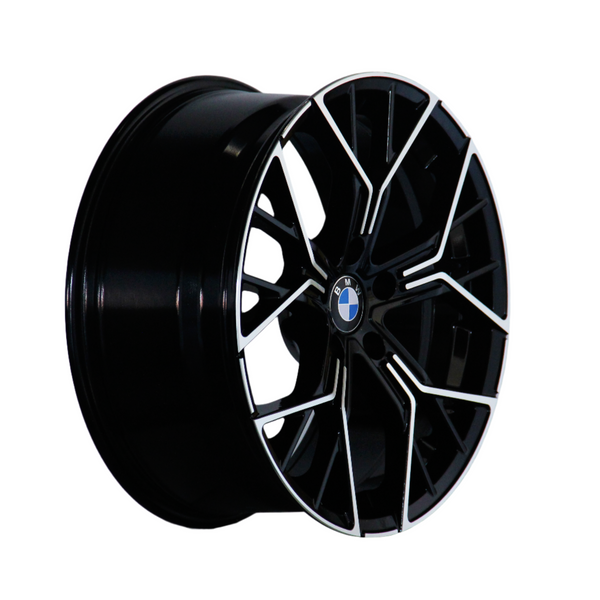 A black alloy wheel with intricate silver patterns and a BMW emblem is positioned against a white background, showcasing its glossy finish and angular design.
