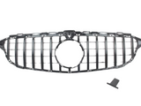 A car grille with vertical slats, designed for a front bumper, includes a circular central opening, placed on a plain white background. A small, detached piece lies nearby.