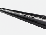 A long, black metal rail features a series of small protrusions along its surface, positioned against a plain white background, suggesting an industrial or architectural context.