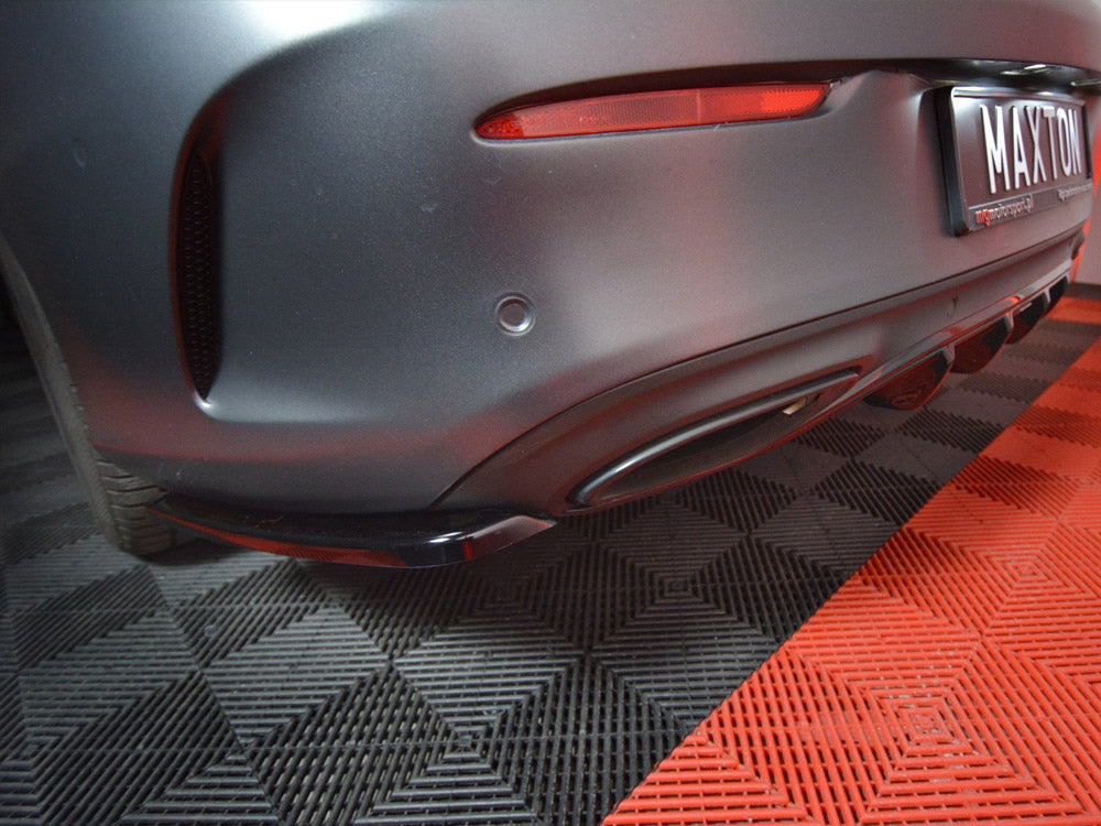 Car rear bumper with diffuser, parked on a checkered black and red mat. A license plate reads "MAXTON" with smaller text below, "maxtondesign.eu."