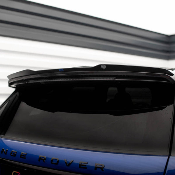 A blue Range Rover parked in a garage. The vehicle's rear is in focus, showcasing tinted windows and a spoiler. The word "Range Rover" is clearly visible on the back.