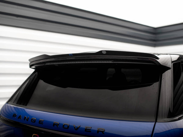 A blue Range Rover parked in a garage. The vehicle's rear is in focus, showcasing tinted windows and a spoiler. The word "Range Rover" is clearly visible on the back.
