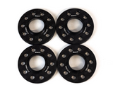 Four black metal wheel spacers with multiple bolt holes are aligned evenly on a white background. They display the brand 