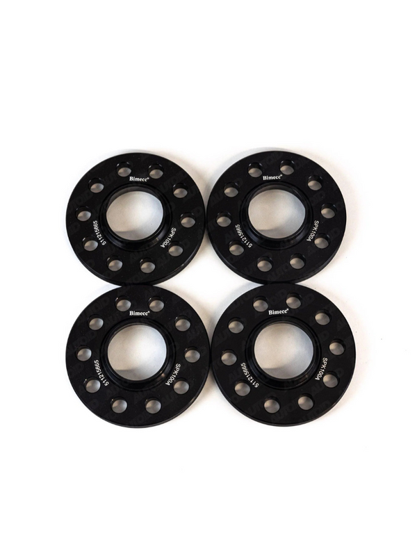 Four black metal wheel spacers with multiple bolt holes are aligned evenly on a white background. They display the brand "BIMECC" and markings "S746064" and "511128585".