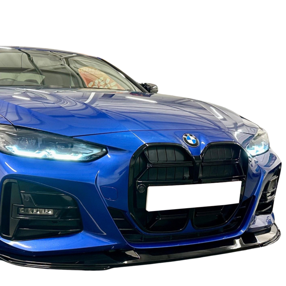 A blue BMW with illuminated headlights is parked indoors, displaying a large black grille and blank license plate, reflecting ceiling lights on its polished surface.