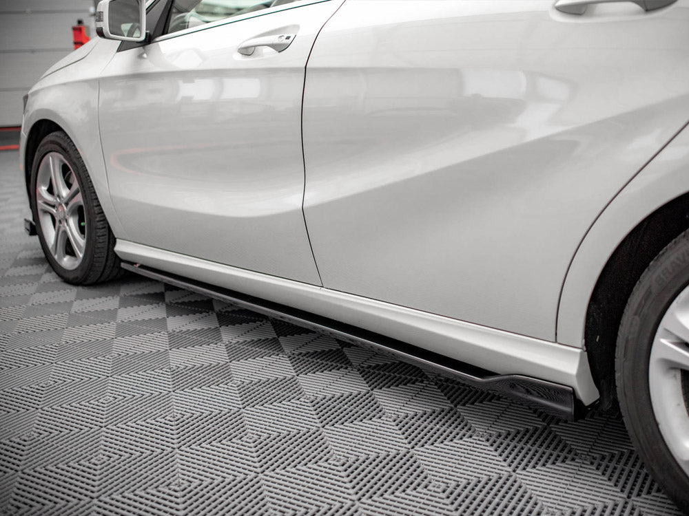 White car parked indoors, highlighting its sleek side profile with aerodynamic contours. The floor has a gray geometric patterned design, and the vehicle rests in a well-lit garage setting.