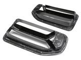 Carbon fiber car vents are displayed on a white background, featuring a sleek, aerodynamic design with two horizontal slats each. A small logo is visible in the corner.