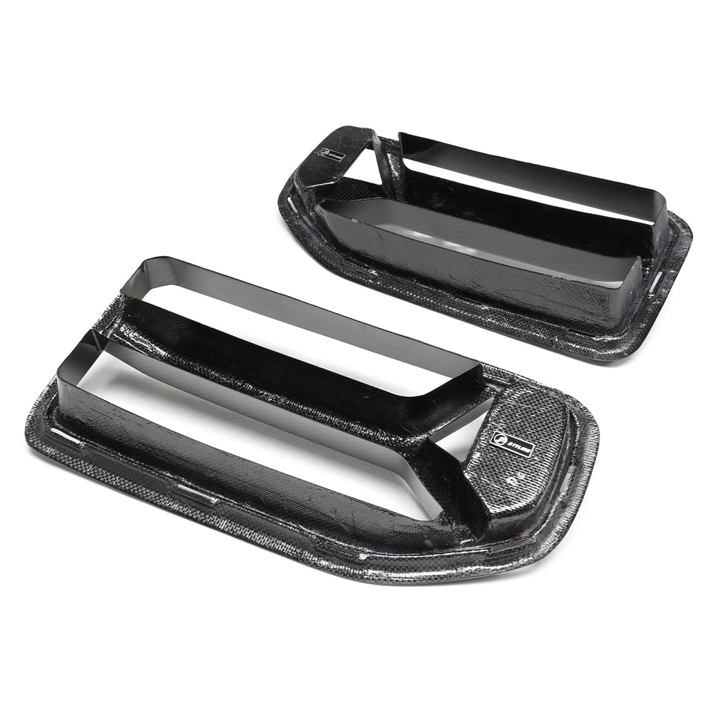 Carbon fiber car vents are displayed on a white background, featuring a sleek, aerodynamic design with two horizontal slats each. A small logo is visible in the corner.