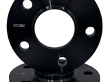 A pair of black wheel spacers feature five bolt holes. One is upright, while the other lies flat beneath. Text on both spacers reads 