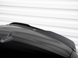 A glossy black car roof features a small antenna fin. The car is parked in front of a white, horizontally-lined wall, and a faint reflective logo is visible on the roof.