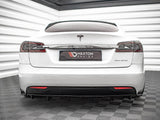 A white Tesla car is parked indoors on a textured floor, with 