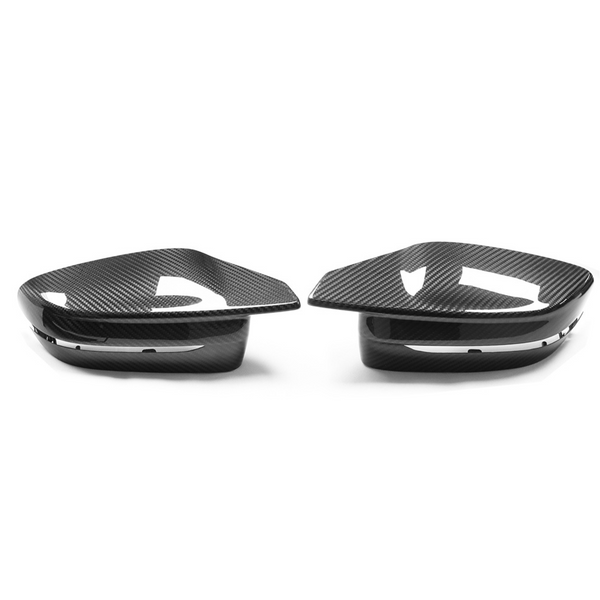 Two carbon fiber side mirror covers rest on a white surface. They feature a sleek, aerodynamic design with glossy finish and subtle contours, positioned symmetrically.