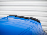 A blue car roof features a black spoiler. Set against a corrugated white background, the reflective surface of the car adds dynamic lines to the composition.