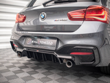 The rear of a gray BMW M440i with visible exhaust pipes is parked on a checkered floor. The license plate reads 