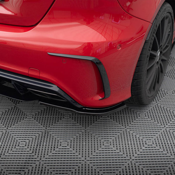 A red car's rear bumper and wheel are shown on a textured, gray, diamond-patterned mat, emphasizing sleek design and detailing.