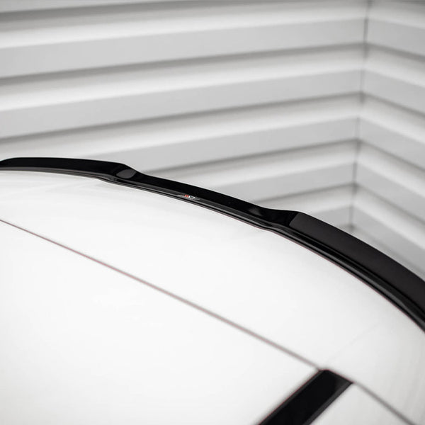 A car roof with a sleek black roof spoiler is parked inside a garage, framed by ribbed metallic walls, adding a modern touch to the minimalistic setting.