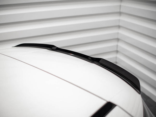 A car roof with a sleek black roof spoiler is parked inside a garage, framed by ribbed metallic walls, adding a modern touch to the minimalistic setting.