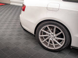 Car rear wheel is parked on a textured gray garage floor. The white vehicle's body features a visible fuel cap, with red taillight on display in the upper corner.