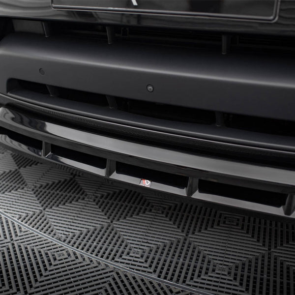 A black car's front bumper with a sleek design is shown in detail, featuring a small "3D" logo. It rests on a geometric-patterned mat.