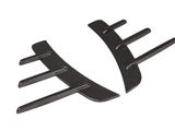Two black carbon fiber car accessories with curved shapes and protruding fins are positioned parallel to each other on a plain white background.
