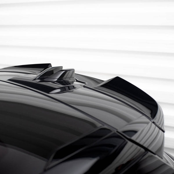 A reflective black car roof features dual roof fins, set against a softly lit, horizontal white background, emphasizing sleek design and modernity.