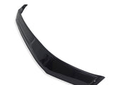 A glossy black car spoiler lies diagonally on a plain white background, showcasing its sleek, curved design and aerodynamic structure.