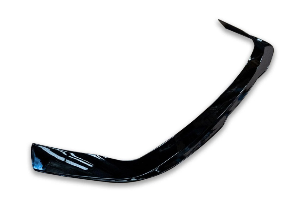 A shiny black car bumper, slightly curved, rests against a plain white background.